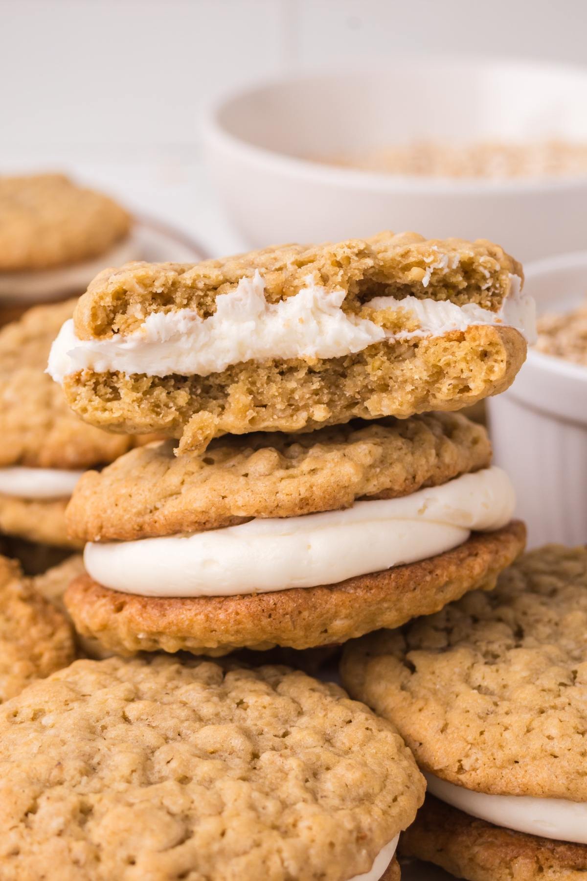 Stack of oatmeal cream pies, with one cookie on top broken in half to show the creamy filling inside.