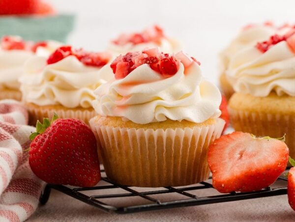 Strawberry Shortcake Cupcakes: Vanilla cupcakes with whipped cream frosting and chopped strawberries, surrounded by fresh strawberries.