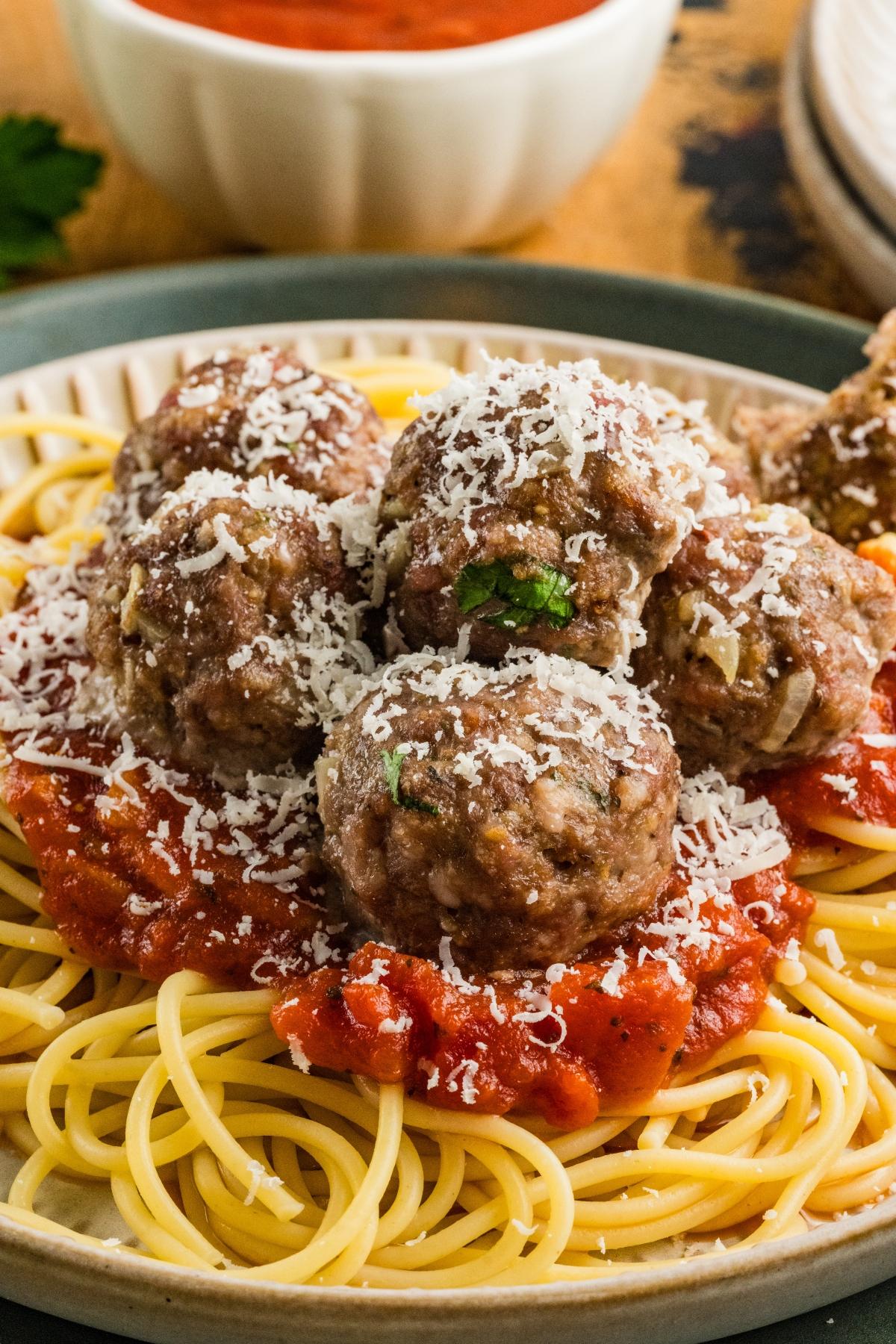 A plate of spaghetti topped with tomato sauce, meatballs, and grated cheese.