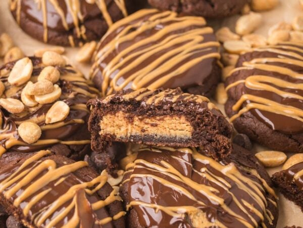 Buckeye Cookies: Chocolate cookies with peanut butter filling, topped with chocolate, peanut butter drizzle, and crunchy peanuts.