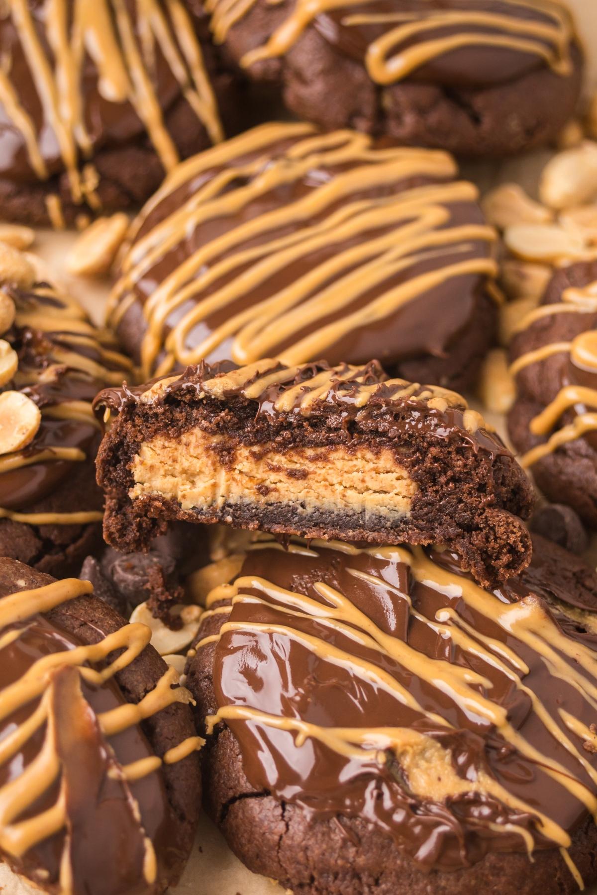 Chocolate cookies with peanut butter drizzle, one cookie split to reveal a creamy peanut butter center.