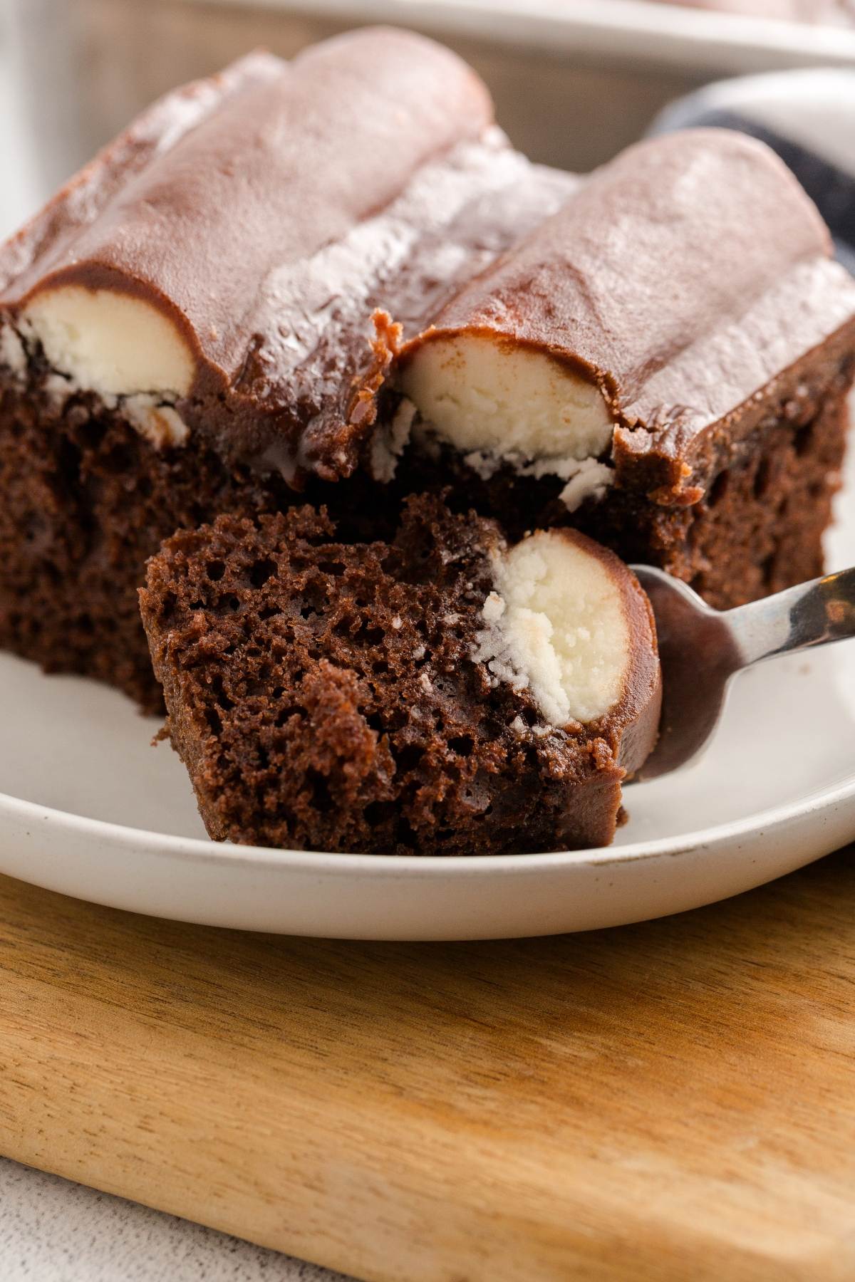 A fork holds a piece of chocolate cake with a creamy coconut filling and chocolate frosting.