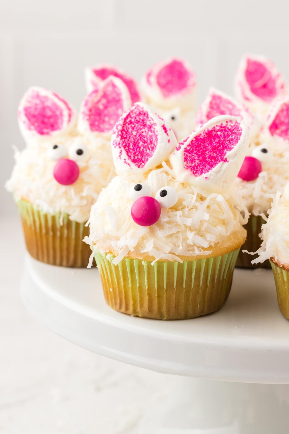 Cupcakes decorated as bunnies with coconut, pink candy noses, candy eyes, and marshmallow ears.