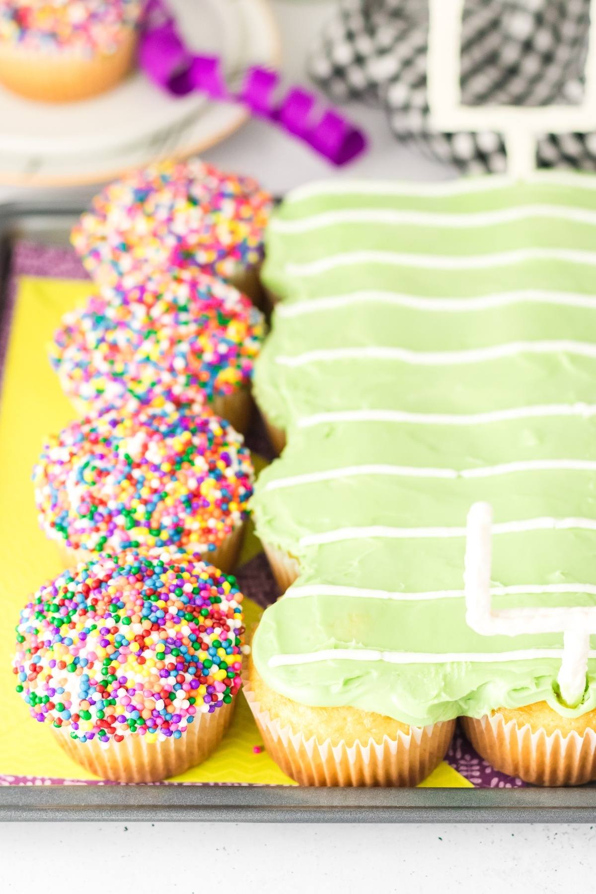Cupcakes with rainbow sprinkles next to green frosted cupcakes decorated like a football field.