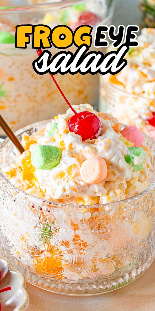 Glass bowl of creamy Frog Eye Salad topped with a cherry and colorful marshmallows, with text "Frog Eye Salad.