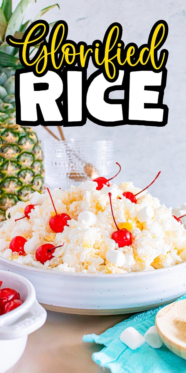 A bowl of glorified rice topped with cherries and marshmallows sits invitingly, with a pineapple in the background.