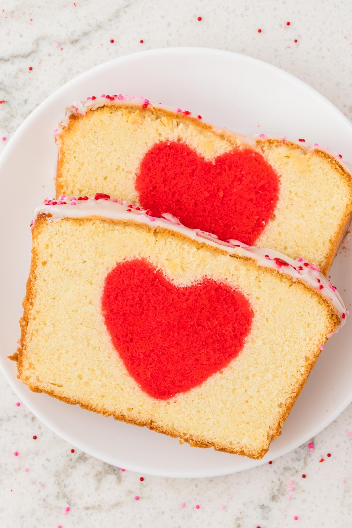 Two slices of hidden heart cake with a red heart shape in the center, served on a white plate.
