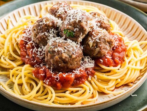A plate of spaghetti topped with tomato sauce, best Italian meatballs, and grated cheese.