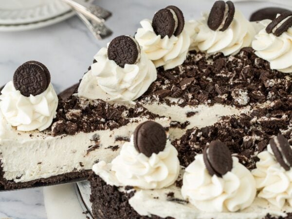 No Bake Oreo Cheesecake topped with whipped cream swirls and mini chocolate sandwich cookies on a plate.