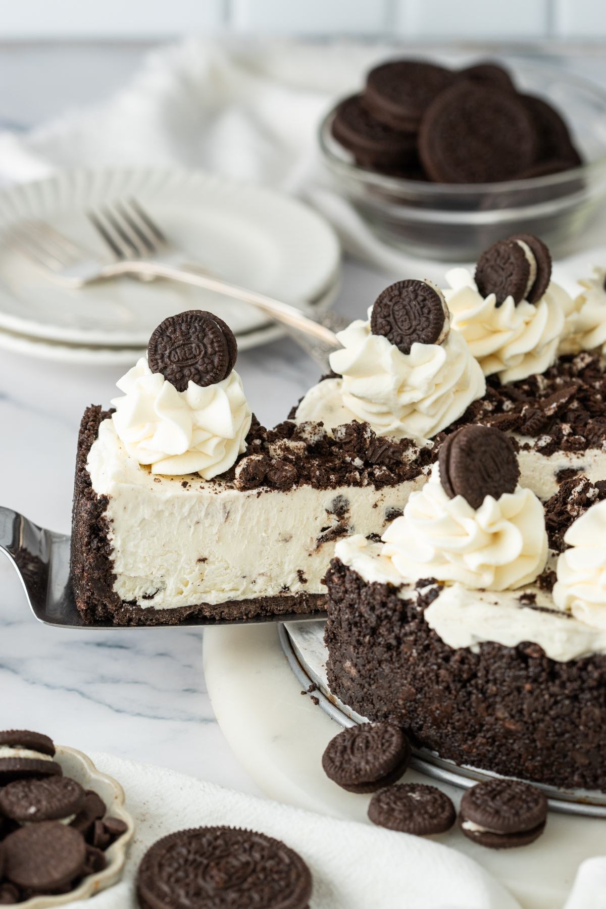 A slice of cookies and cream cheesecake with whipped topping and mini chocolate cookies.