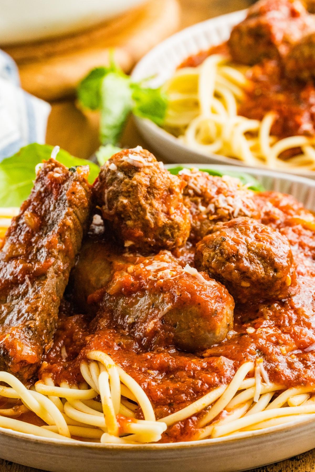 A plate of spaghetti topped with tomato sauce, meatballs, and slices of sausage.