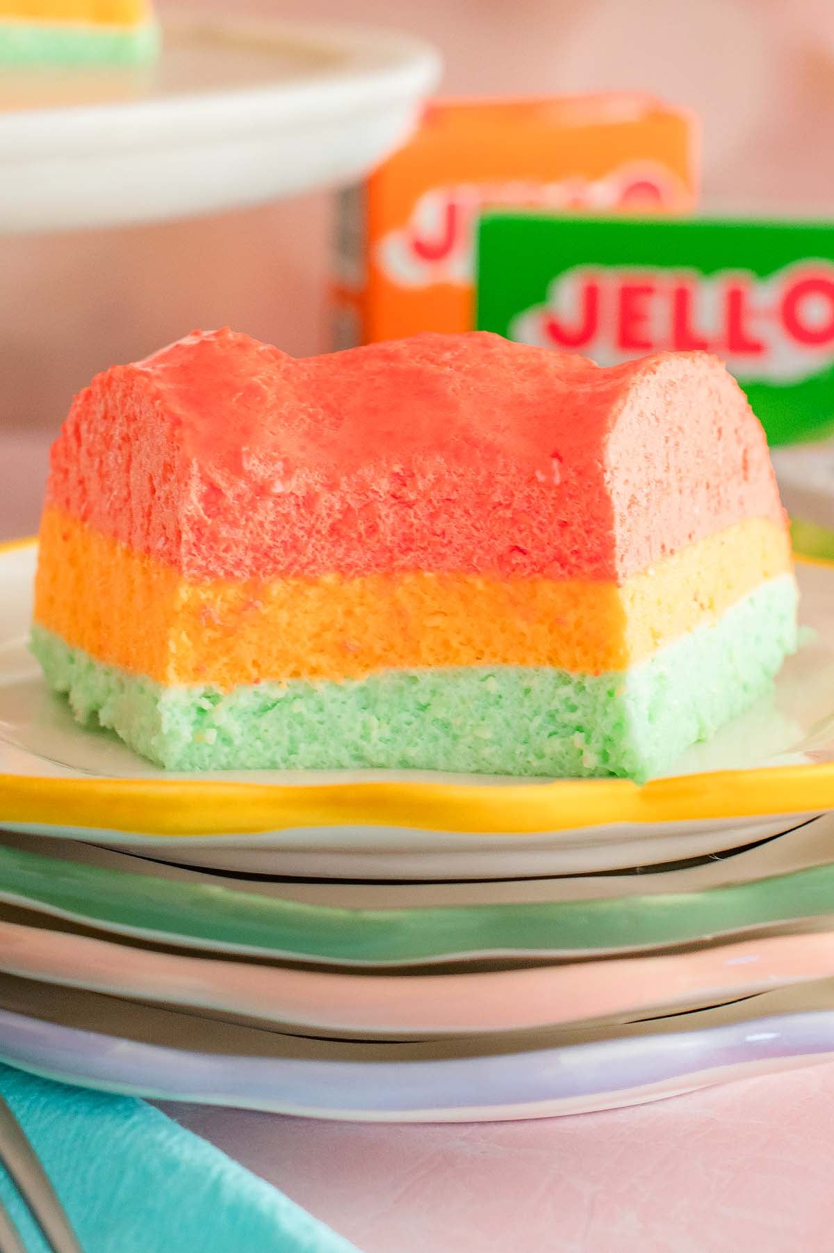 A colorful Sherbet Layered Jello Mold dessert with vibrant pink, orange, and green layers beautifully arranged on a plate.