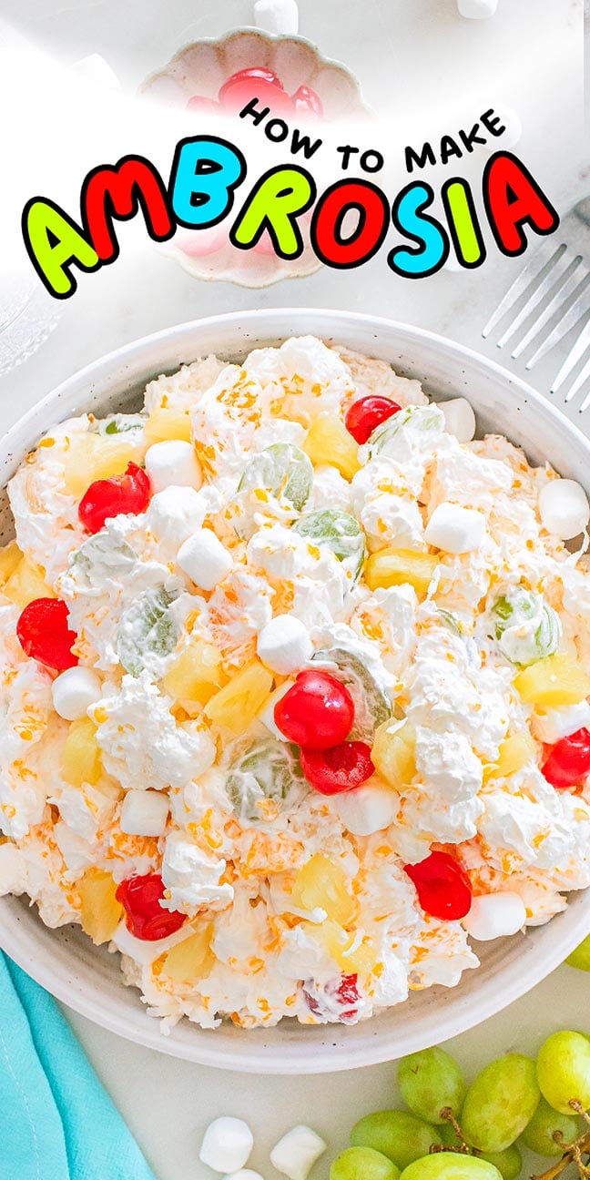A bowl of classic ambrosia salad with whipped cream, cherries, pineapple, grapes, and fluffy marshmallows.