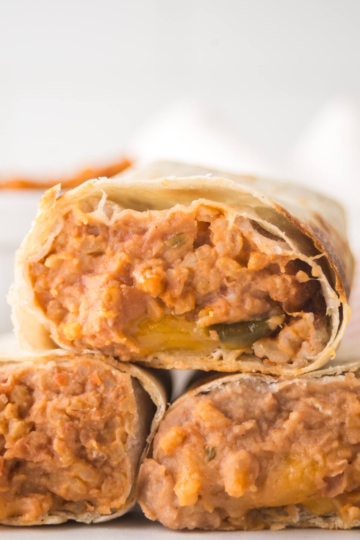 Close-up of a bean and cheese burrito sliced in half, showing the creamy filling inside a flour tortilla.
