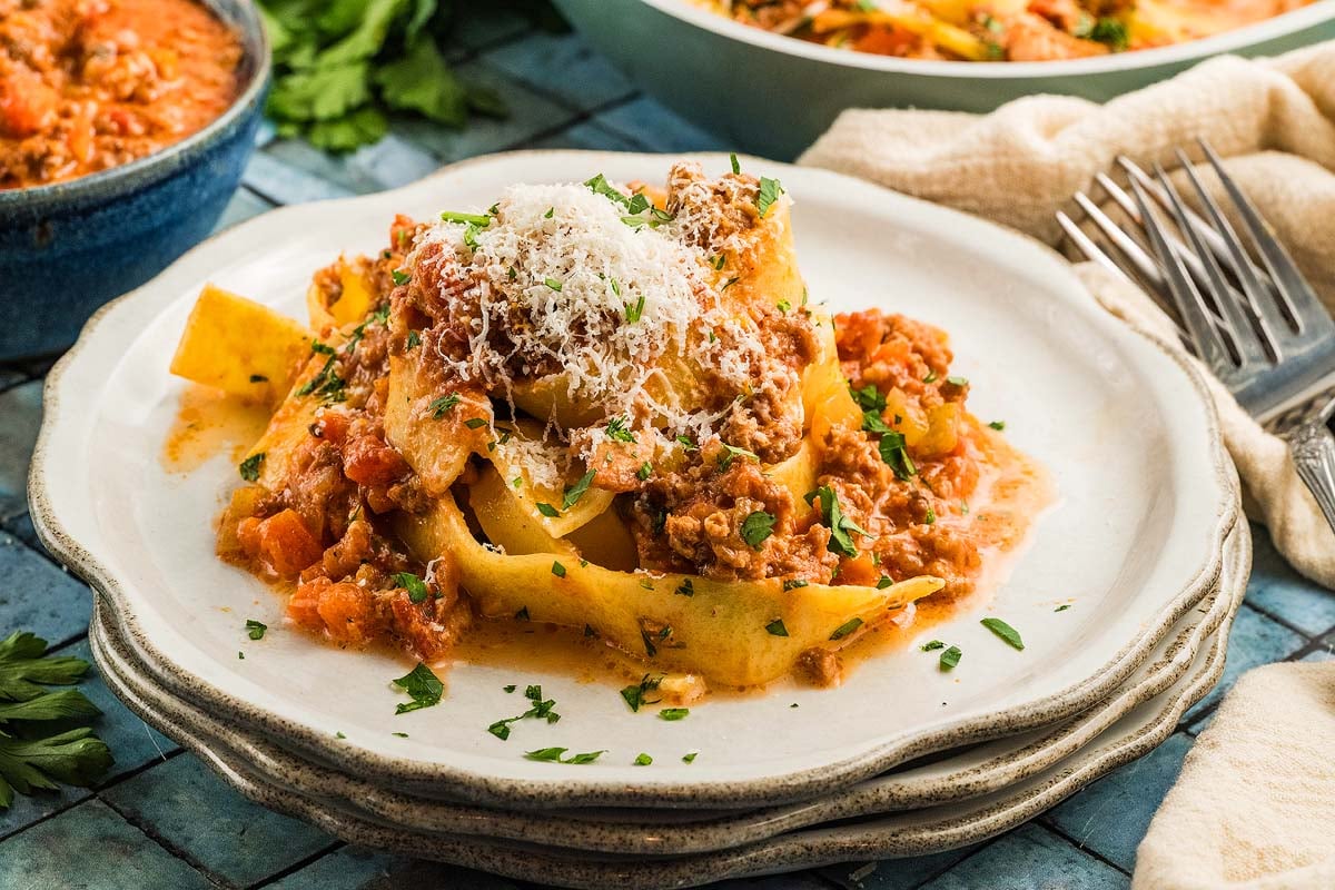 A plate of pasta with authentic Bolognese sauce, topped with grated cheese and chopped parsley.