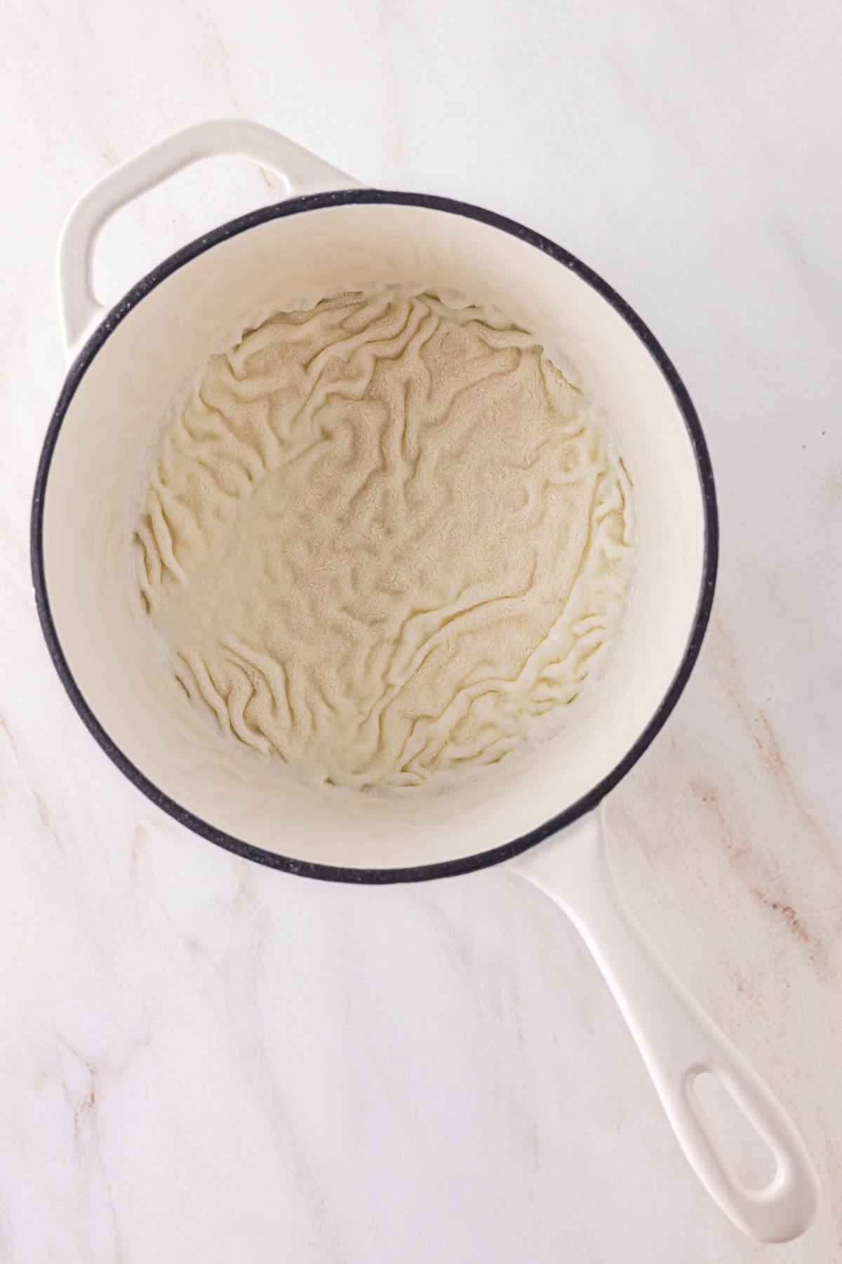 A white pot with dried milk residue creating wavy lines on the bottom.