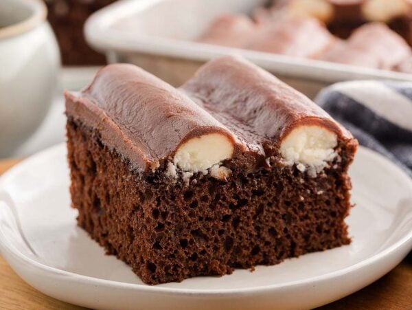 A slice of bumpy cake with a creamy filling sits on a white plate, accompanied by a fork and napkin.