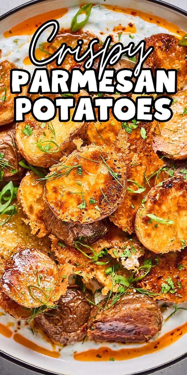 Close-up of Crispy Parmesan Potatoes, perfectly roasted and topped with parmesan cheese, then garnished with fresh green herbs.