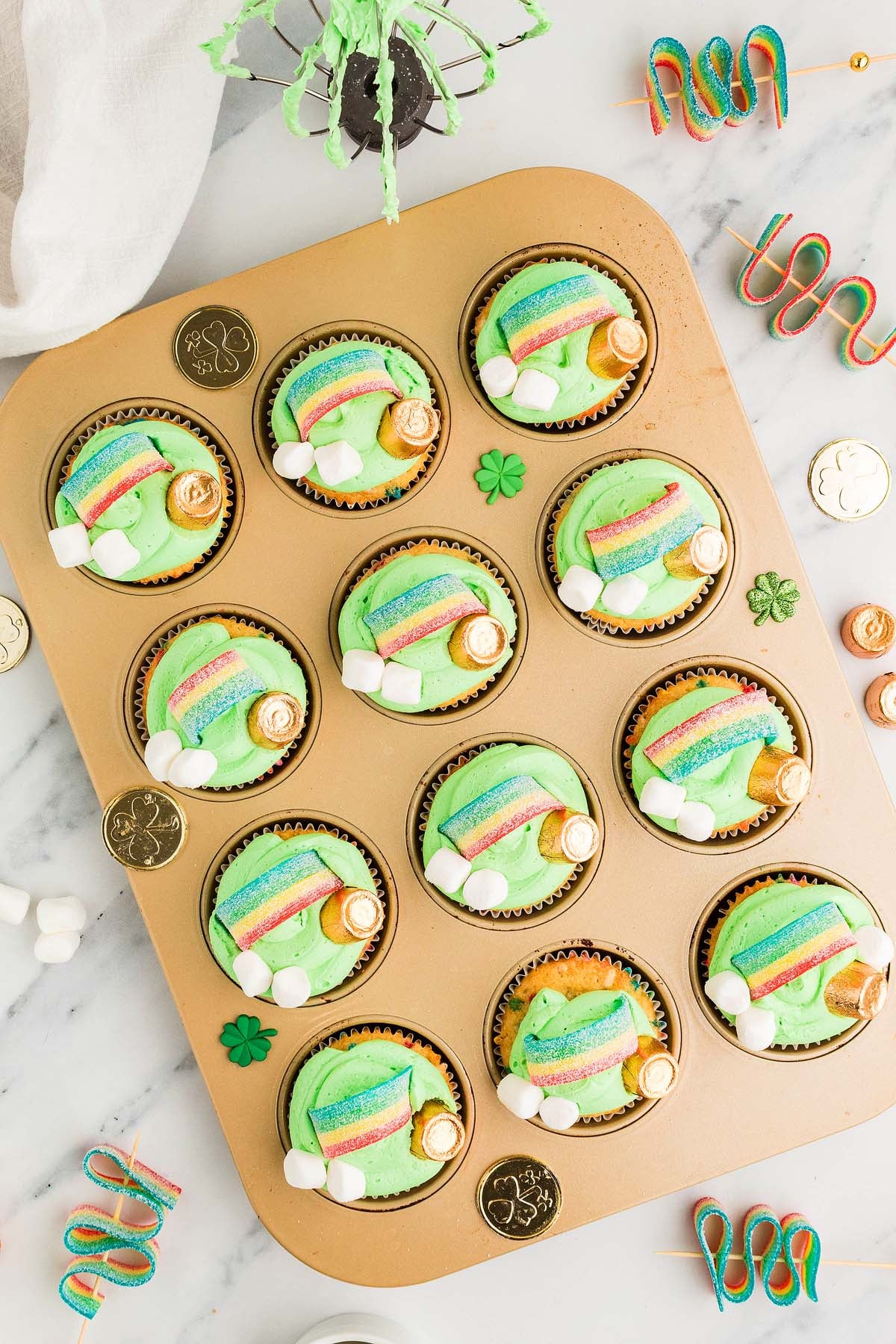 A tray of St. Patrick's Day Cupcakes features green frosting and gold coins, perfect for celebrating the holiday.