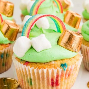 St. Patrick's Day Cupcakes topped with green frosting, candy rainbows, gold-wrapped chocolates, and mini marshmallows for a festive treat.