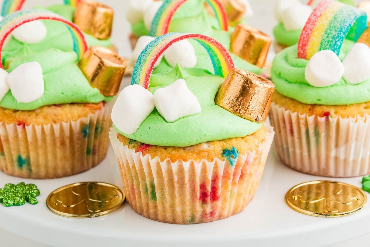 St. Patrick's Day Cupcakes decorated with green frosting, rainbow candy, gold coins, marshmallows, and chocolates make for a festive and colorful treat.
