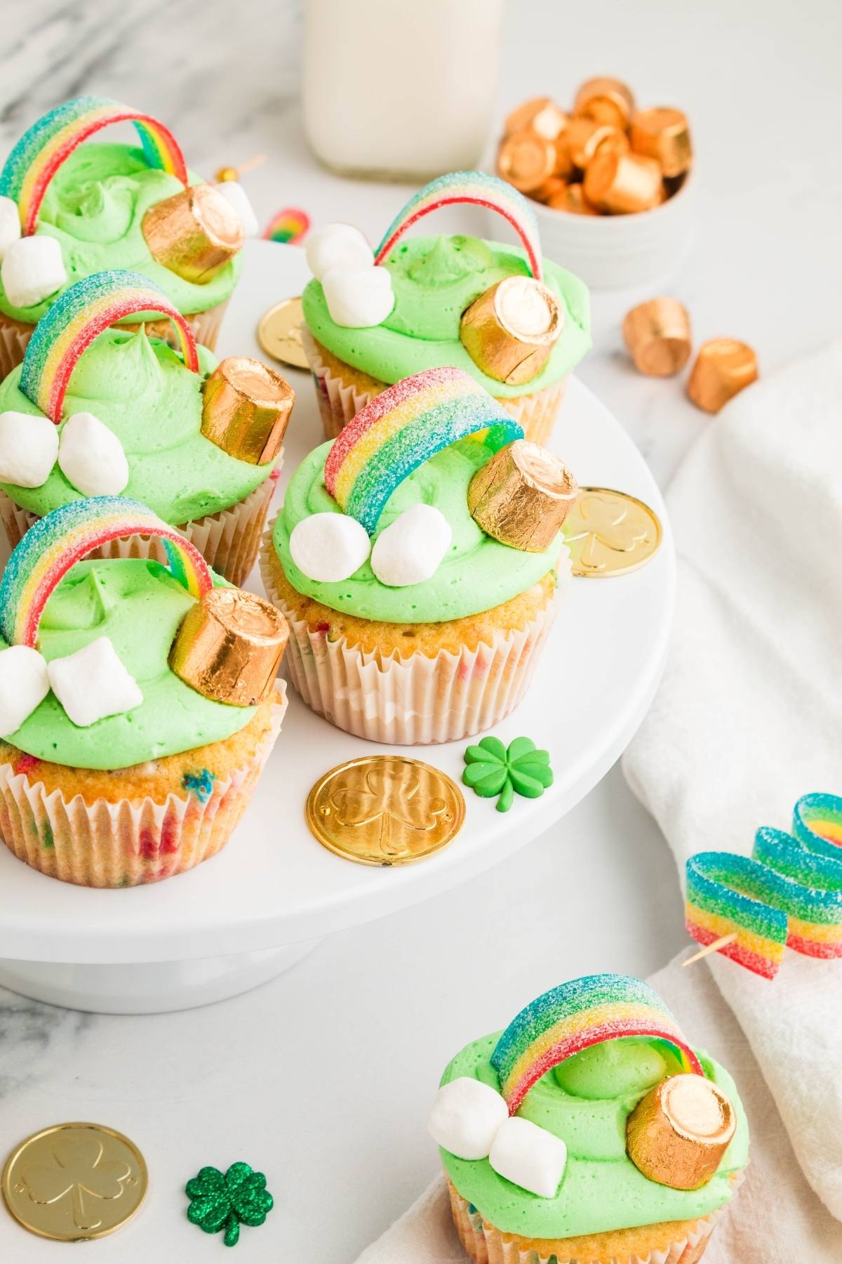 St. Patrick&rsquo;s Day cupcakes with green frosting, rainbow candy, gold coins, Rolos, and mini marshmallows.