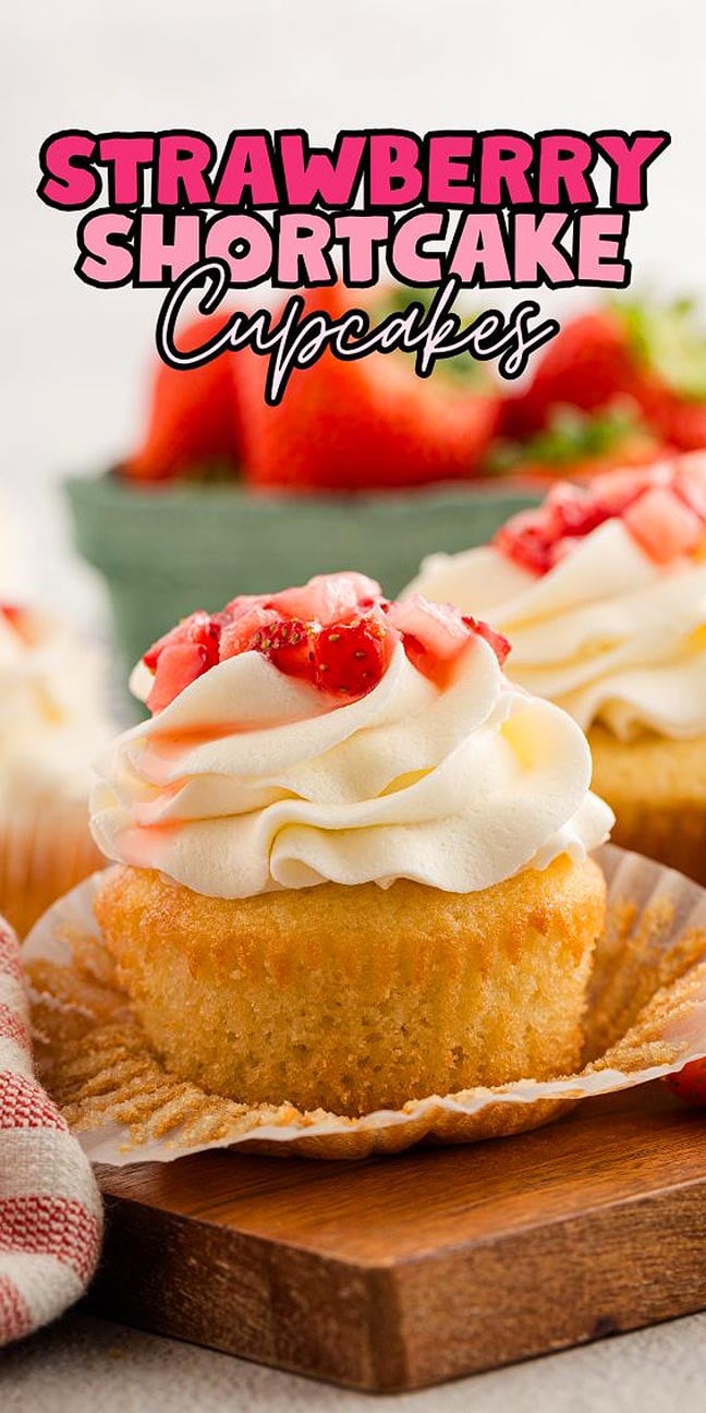 A Strawberry Shortcake Cupcake topped with whipped cream and fresh strawberry topping, featuring the text "Strawberry Shortcake Cupcakes.