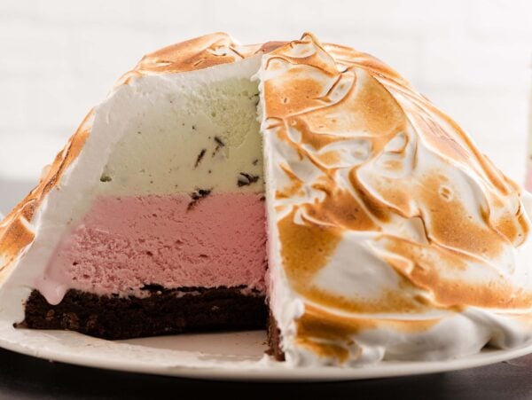 A sliced Baked Alaska with layers of ice cream and cake, all blanketed in golden toasted meringue.