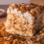 A close-up of a creamy Biscoff Tiramisu slice being lifted from a tray with a spatula, showcasing its luscious layers.