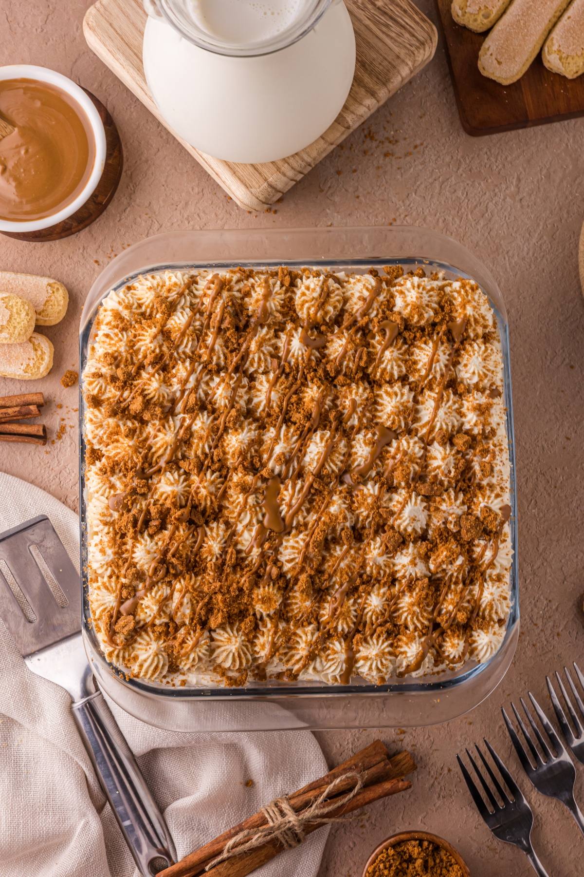 A square Biscoff tiramisu dessert topped with cream, crumbs, and drizzle.