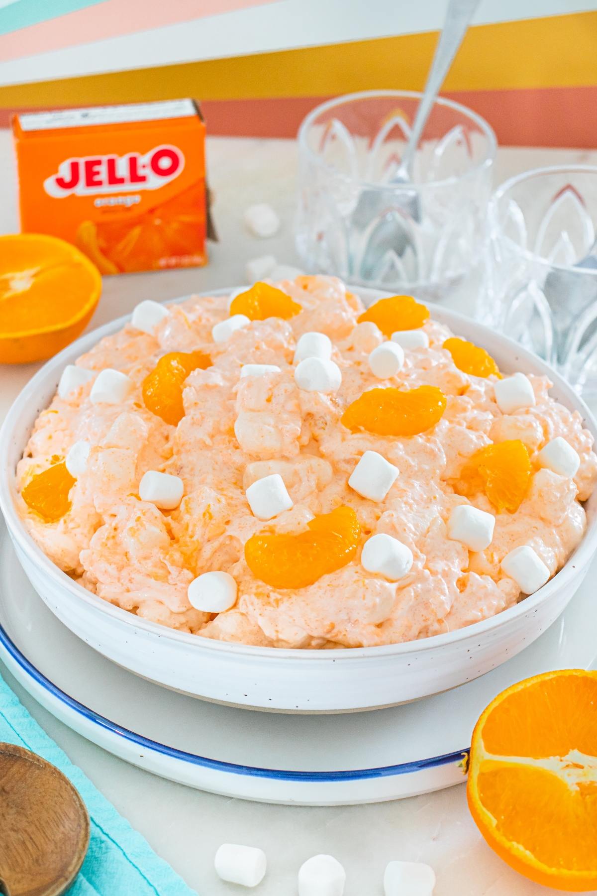A bowl of Cottage cheese jello salad with mandarin slices and mini marshmallows, next to an orange and Jello box.