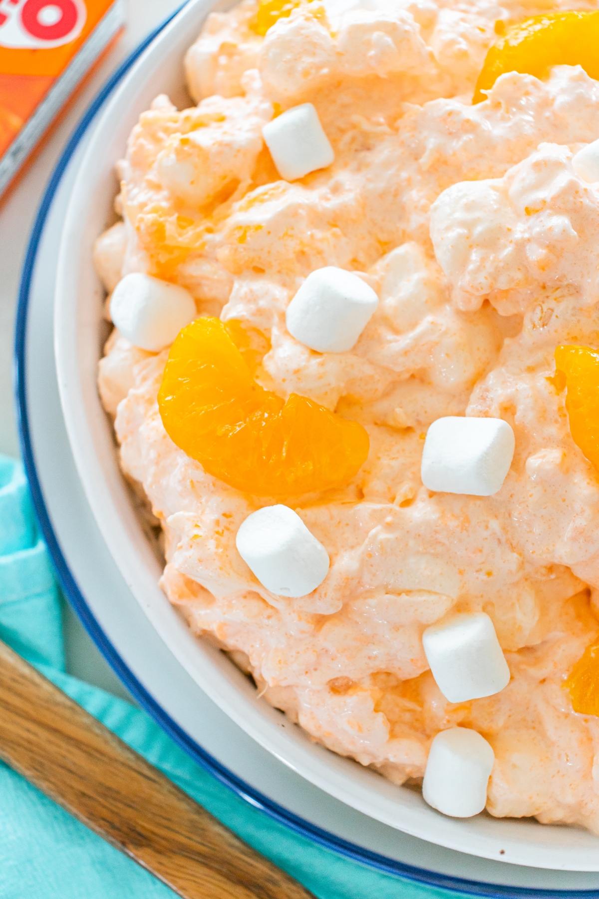 A bowl of Cottage cheese jello salad with mini marshmallows and mandarin orange slices on top.