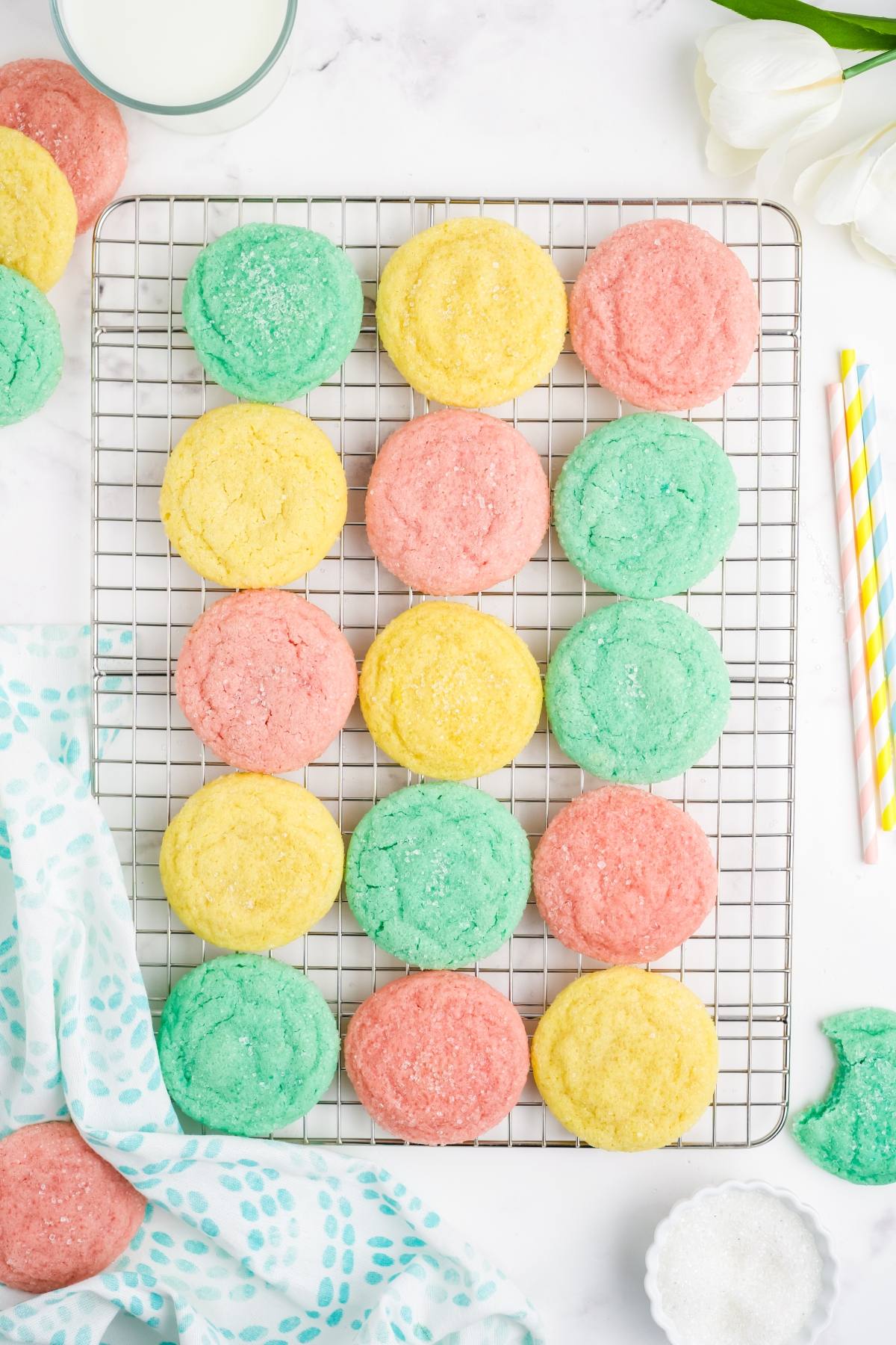Colorful yellow, pink, and green sugar Kool-Aid cookies arranged on a cooling rack, viewed from above.
