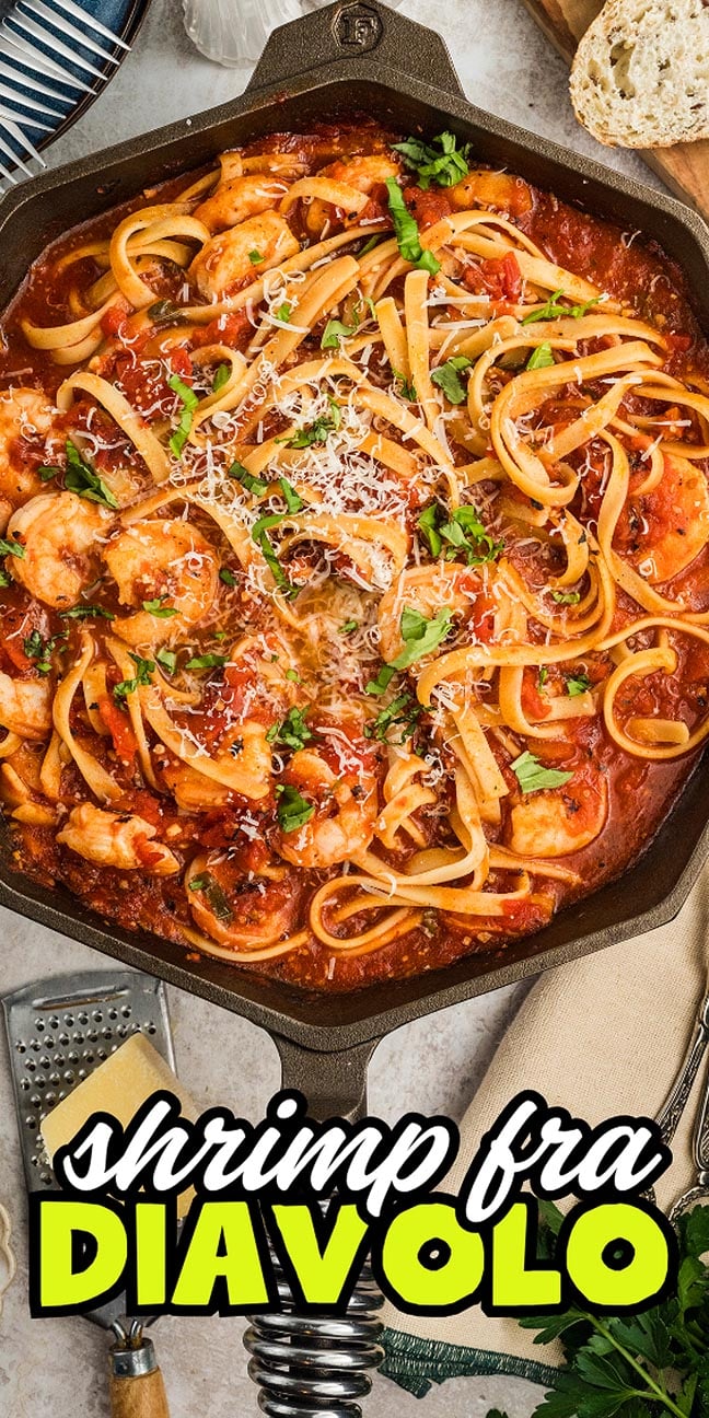 Overhead view of Shrimp fra Diavolo pasta in a skillet, topped with fresh herbs and grated cheese.