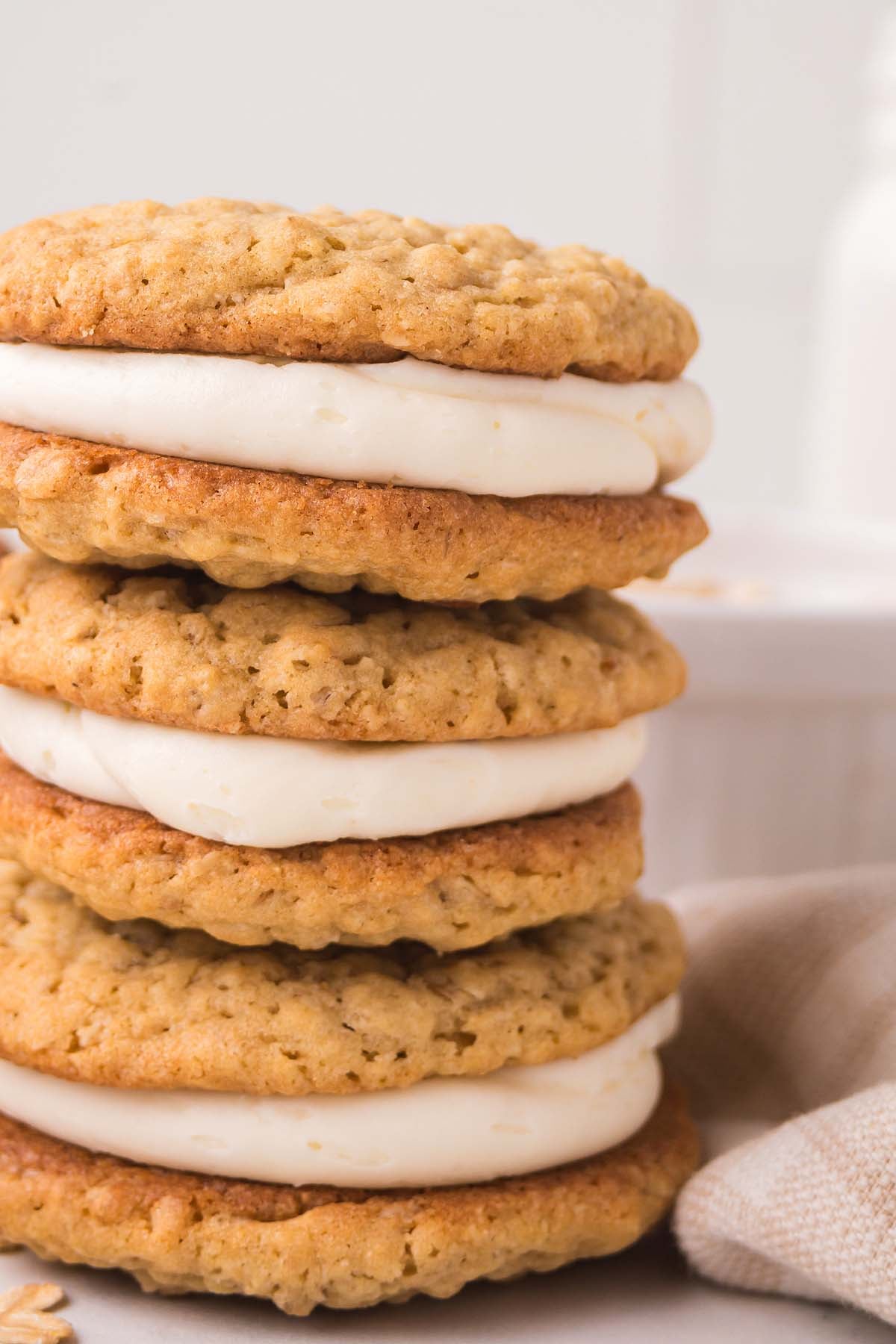 A stack of Homemade Oatmeal Cream Pies, each cookie layered with creamy filling, arranged neatly on a light surface.