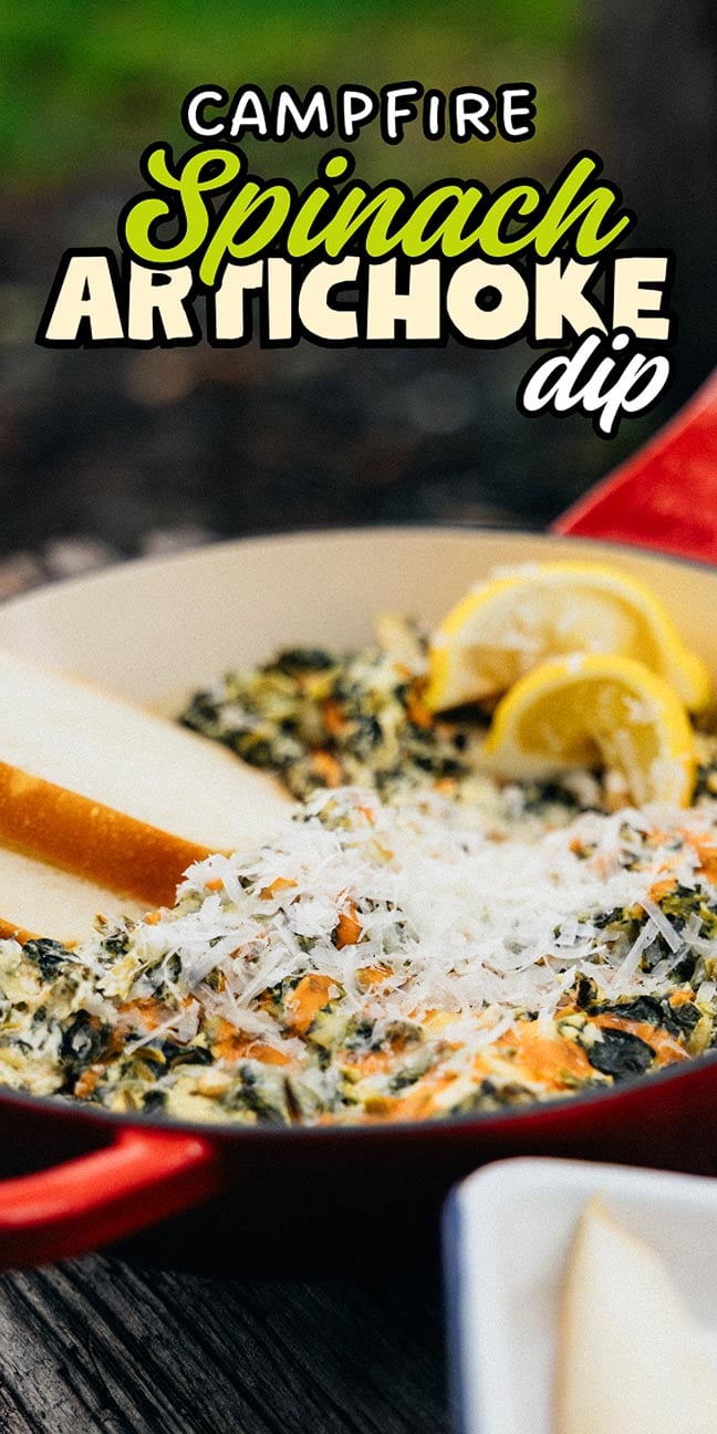 A skillet of campfire spinach artichoke dip topped with cheese and lemon wedges, served with fresh pear slices on the side.