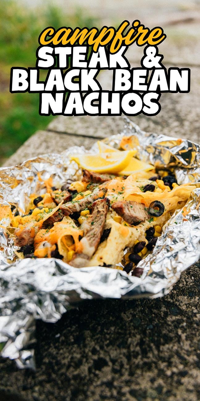 Foil packet of Campfire Steak and Black Bean Nachos with melted cheese on an outdoor surface, text overlay on top.