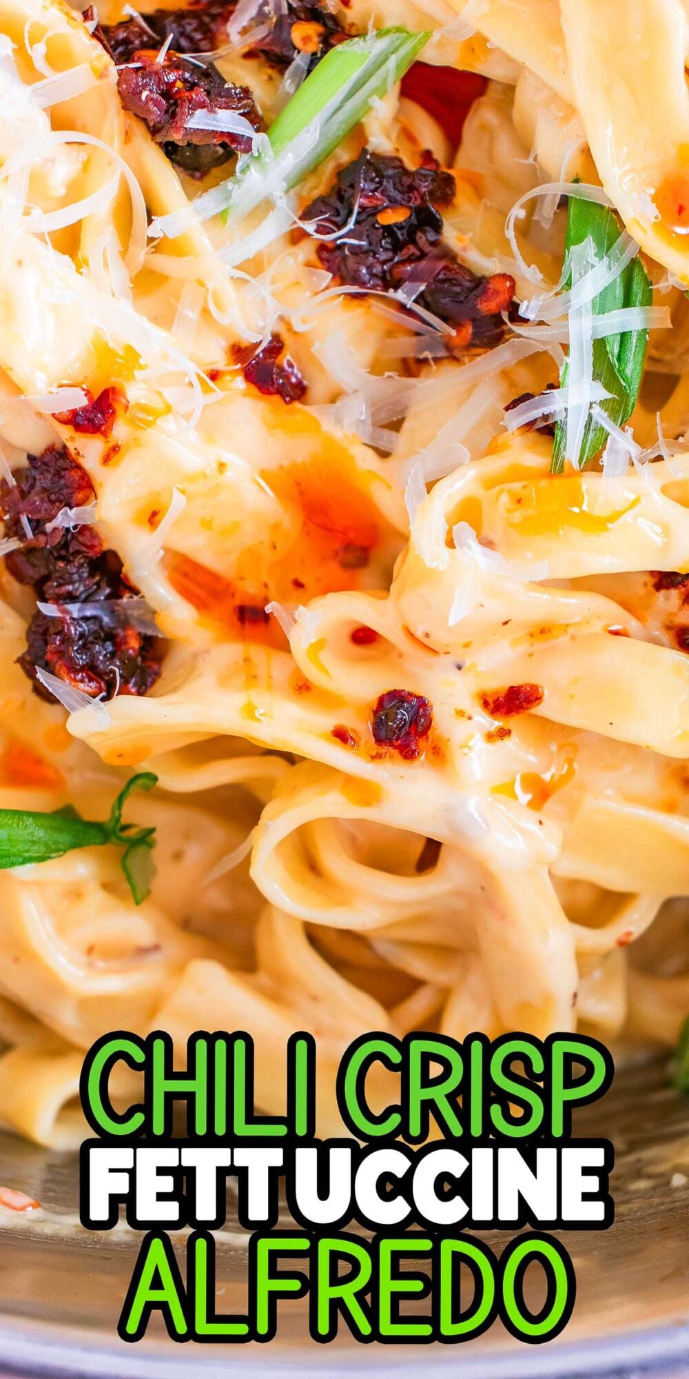 Close-up of Chili Crisp Fettuccine Alfredo topped with grated cheese and fresh green garnish. Text: "Chili Crisp Fettuccine Alfredo.