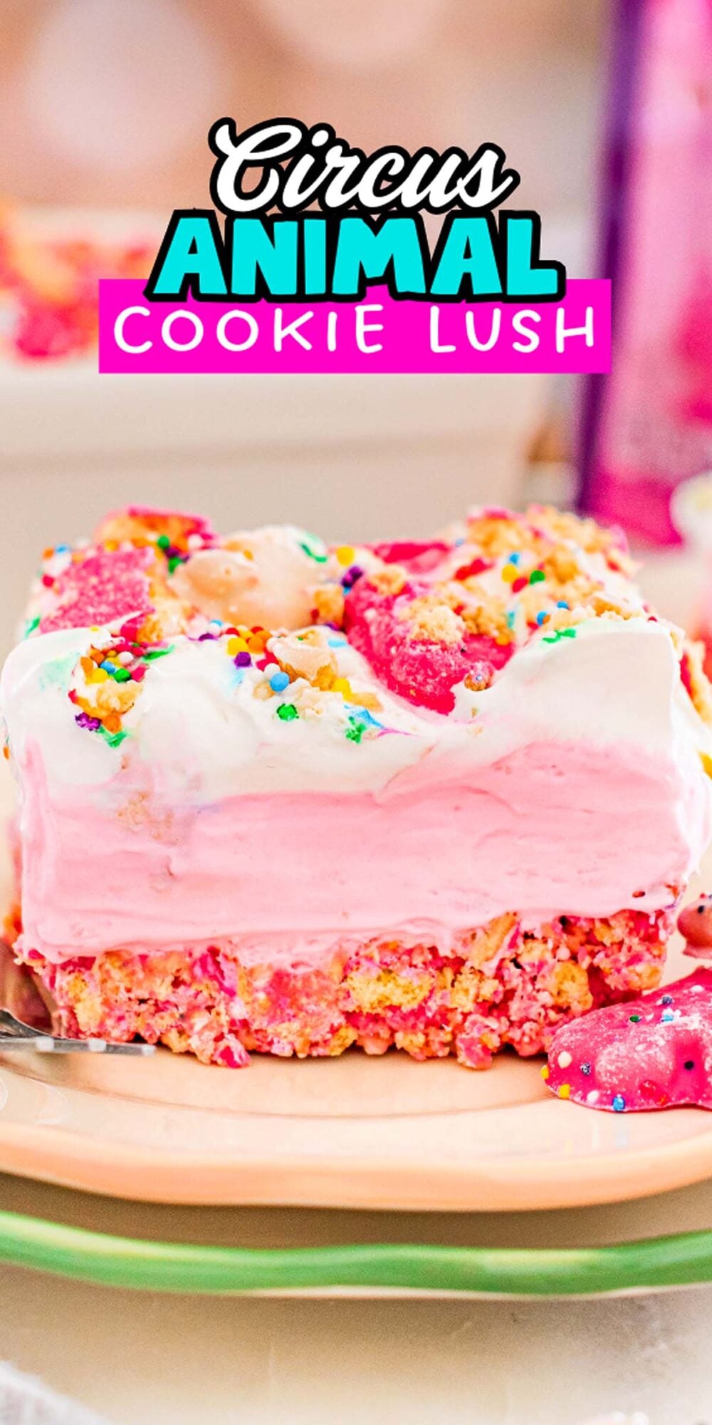 A slice of Circus Animal Cookie Lush, with pink and white layers, topped with sprinkles and circus animal cookies on a plate.