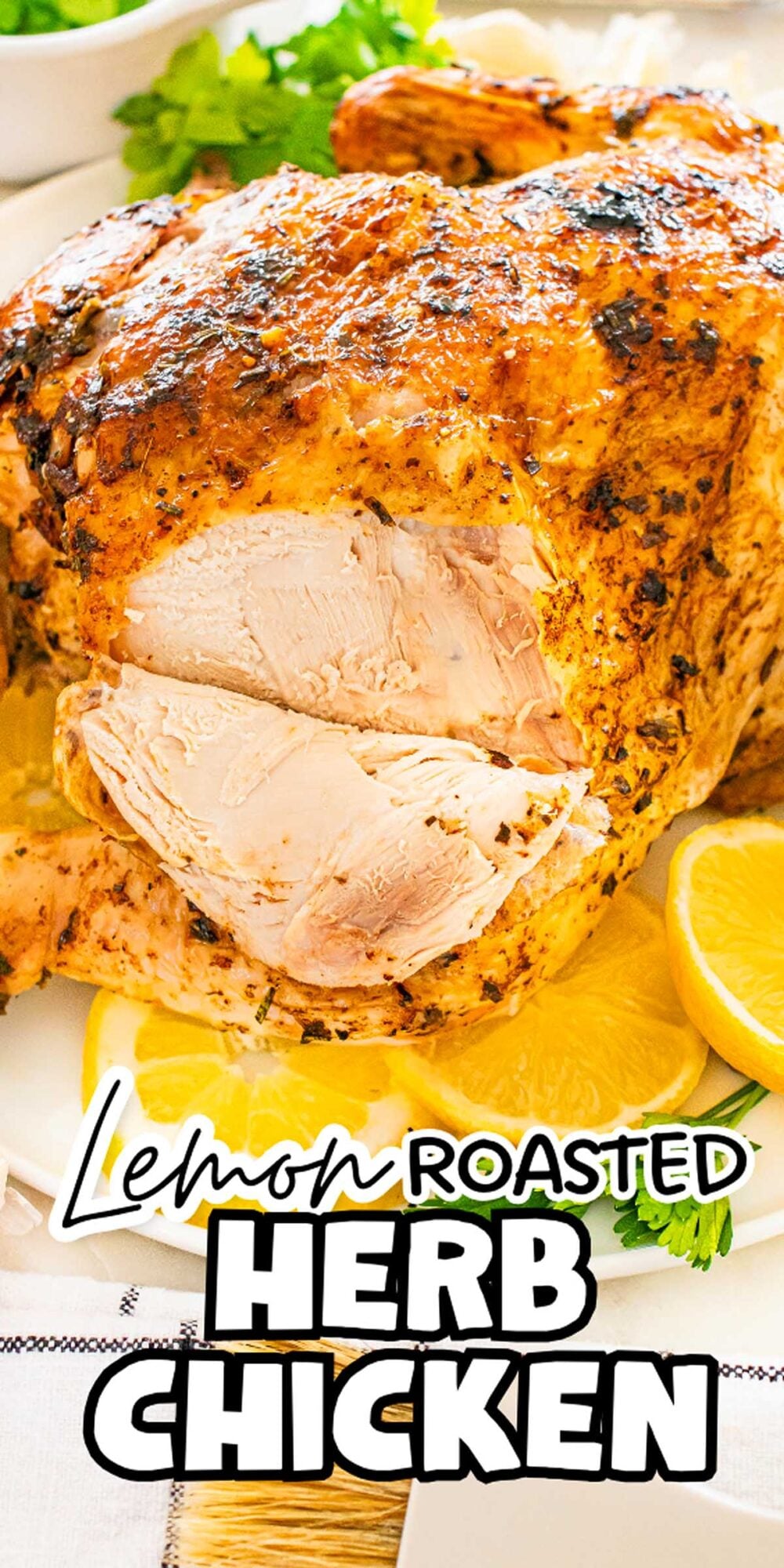 Lemon herb roasted chicken with crispy skin, sliced to reveal juicy meat, garnished with lemon slices and fresh herbs on a white plate.