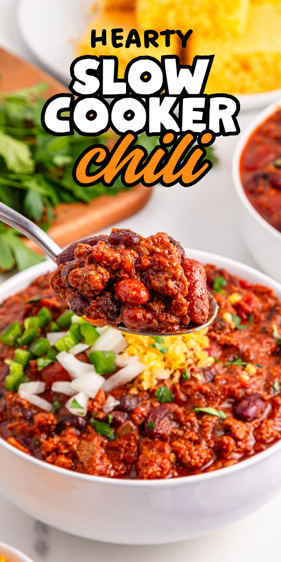 A spoonful of hearty slow cooker chili above a bowl topped with onions, cheese, and jalapeños. This classic slow cooker chili is the perfect comfort food for any occasion.