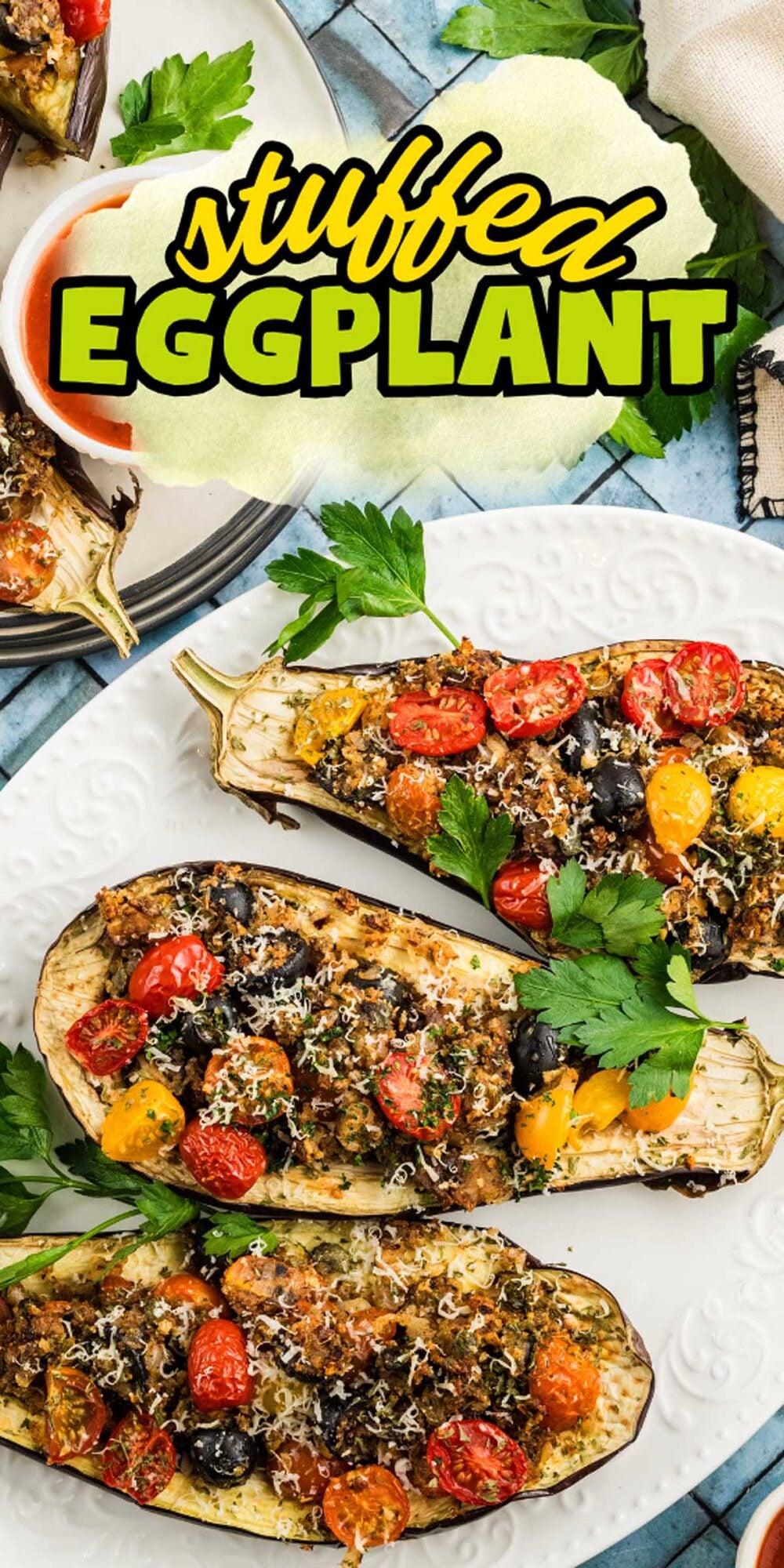 Three halved stuffed eggplants filled with tomatoes, olives, herbs, and cheese are arranged on a white plate, labeled "Stuffed Eggplant.