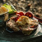 Vanilla ice cream served on a fruit-topped cobbler, with peaches and rhubarb on the side—an outdoor treat.
