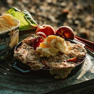 Vanilla ice cream served on a fruit-topped cobbler, with peaches and rhubarb on the side&mdash;an outdoor treat.