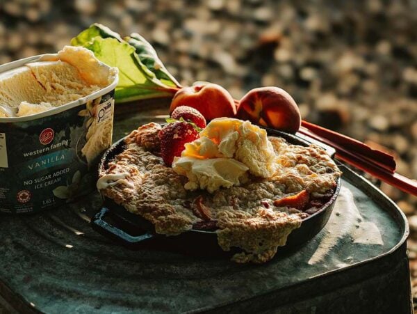 Vanilla ice cream served on a fruit-topped cobbler, with peaches and rhubarb on the side&mdash;an outdoor treat.