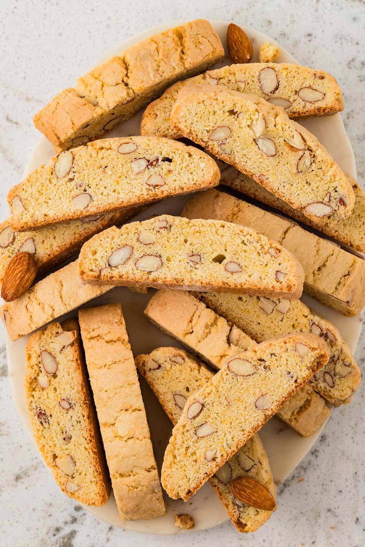 A plate of classic almond biscotti cookies is artfully arranged on a white surface.
