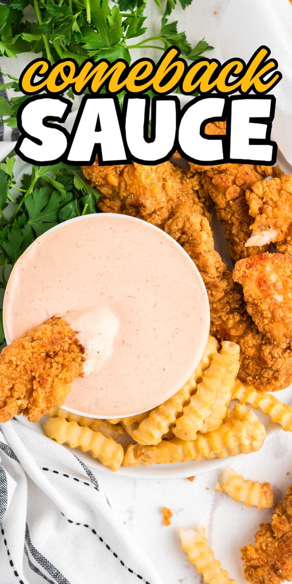 A bowl of creamy Comeback Sauce with fried chicken tenders and crinkle-cut fries on a white plate.