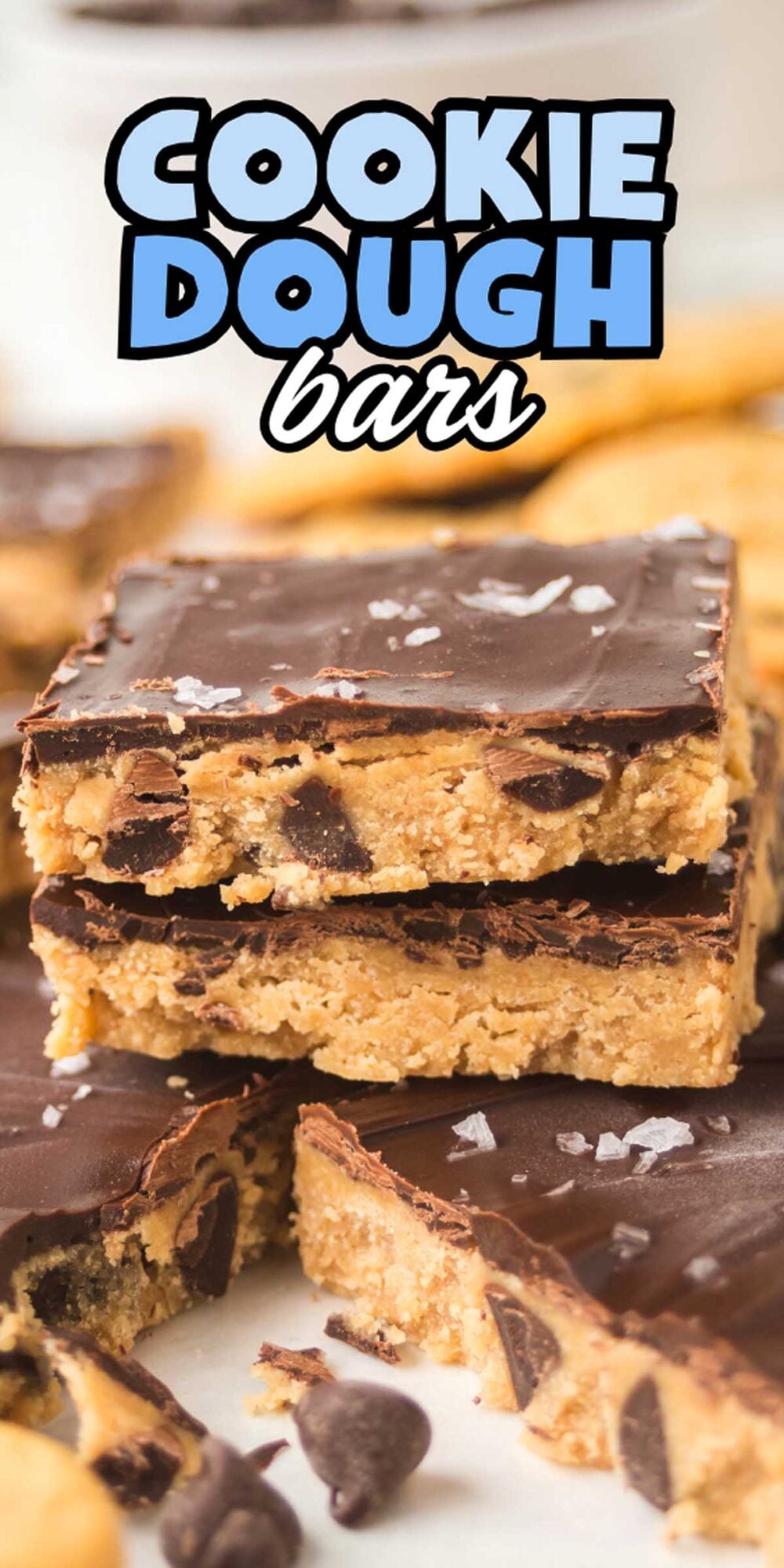Stack of rich Cookie Dough Bars coated in chocolate, with visible chocolate chips and a sprinkle of flaky sea salt on top.