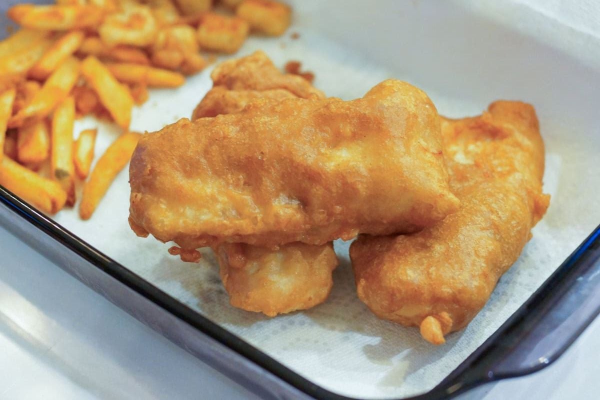 Golden battered fish fillets and fries on a tray lined with white paper, inspired by classic Guinness recipes for a rich, flavorful twist.