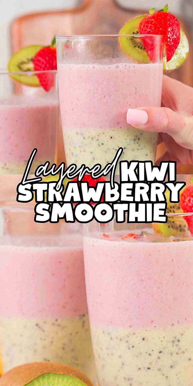 A hand holds a glass of colorful Layered Kiwi Strawberry Smoothie, garnished with fresh fruit slices.